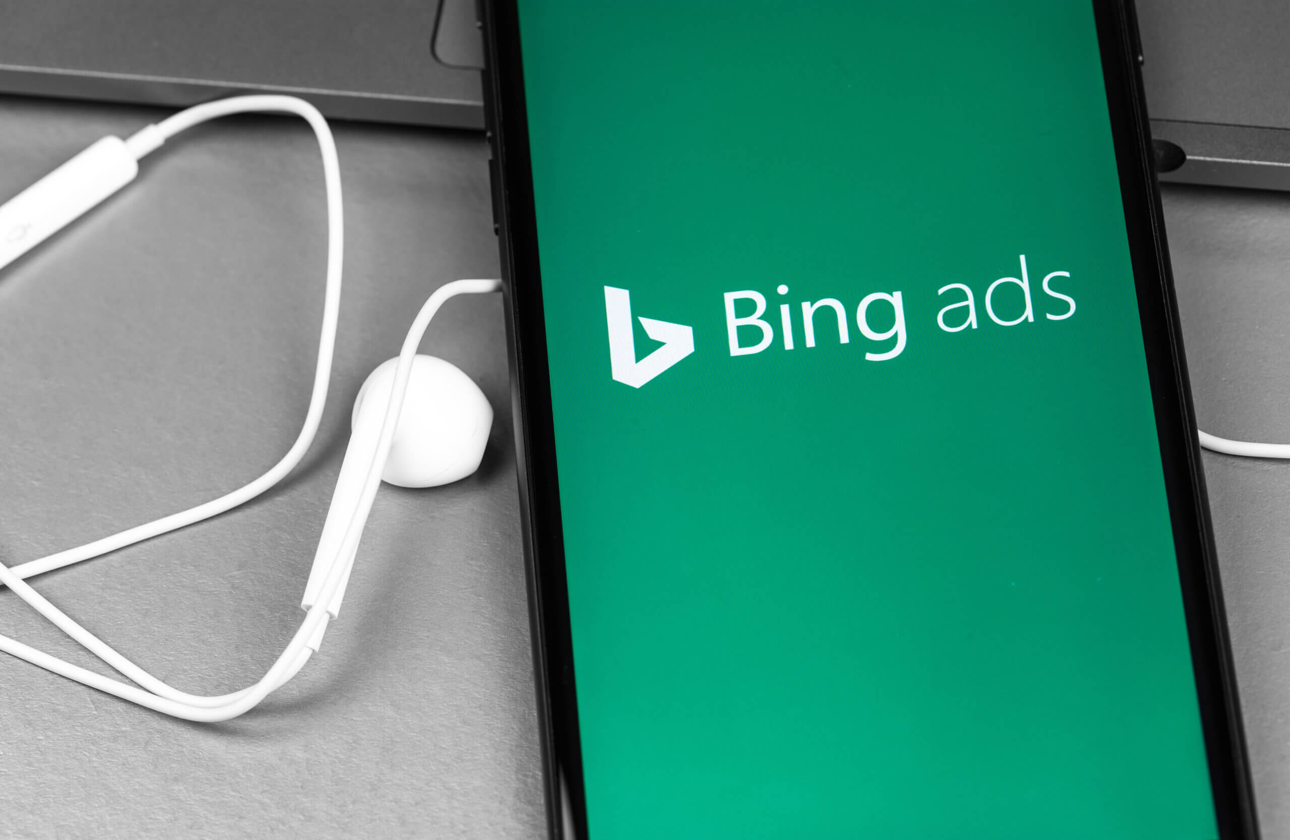 Bing Ads app logo on the screen smartphone with headphones Earpods closeup. Microsoft Advertising is a service that provides pay-per-click advertising like Bing. Moscow, Russia - August 11, 2020